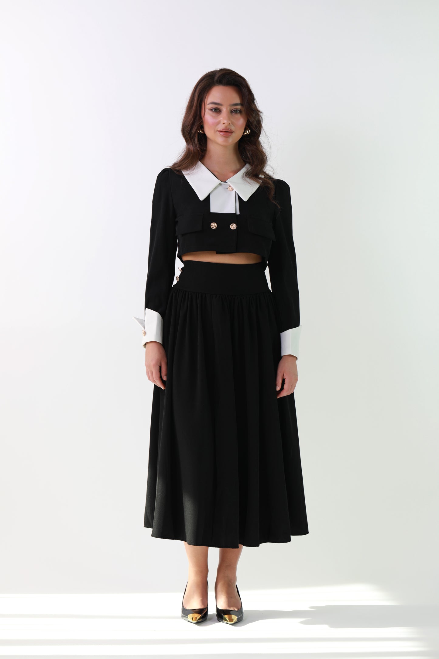 Woman wearing a black outfit with a white collar on a white background