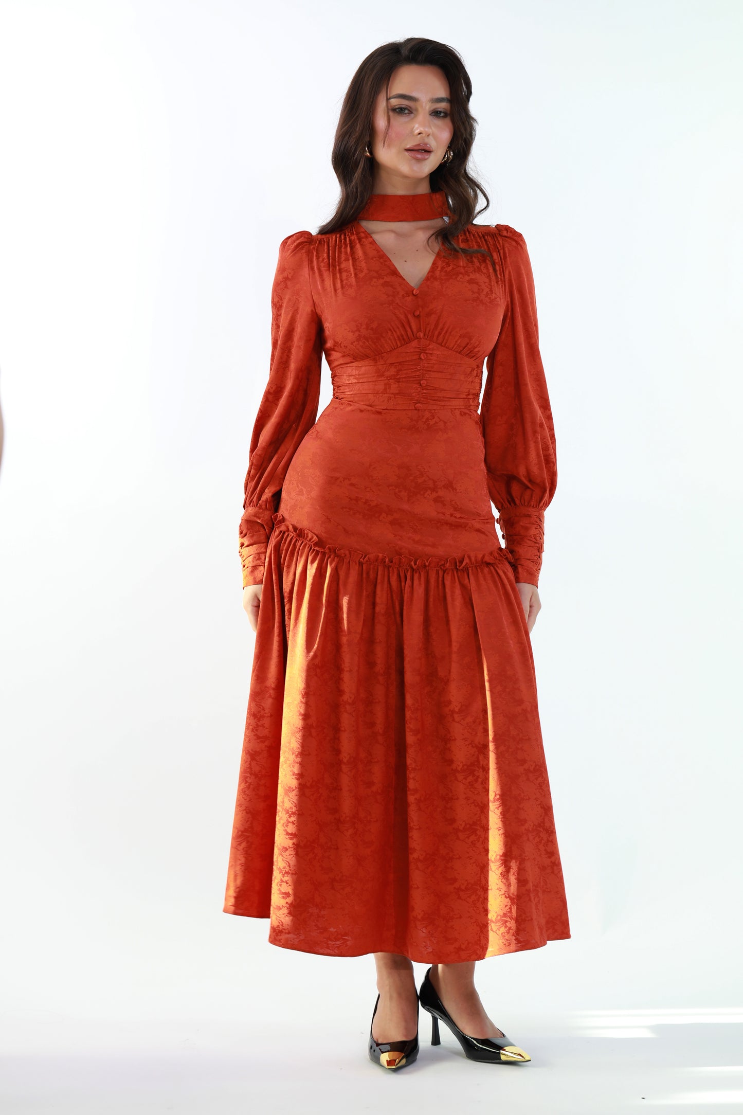 Woman wearing a rust-colored dress with long sleeves on a white background